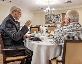 Two men are sitting at a table in a restaurant. Description generated by AI
