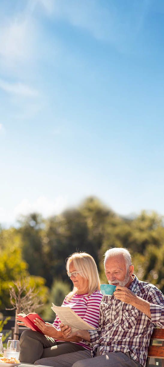 A man and woman sitting on a bench, both holding coffee cups. Description generated by AI