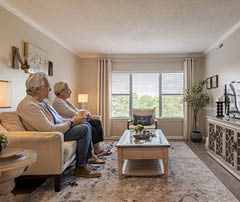 A man and woman sitting on a couch watching TV. Description generated by AI