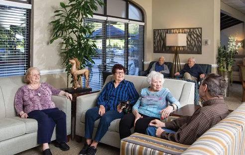 A group of elderly people are sitting in a living room, engaged in conversation. AI generated content